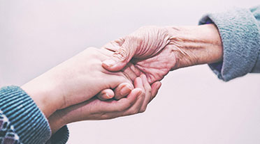 Older person holding hands with younger person