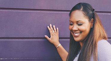 Woman touching purple wall smiling