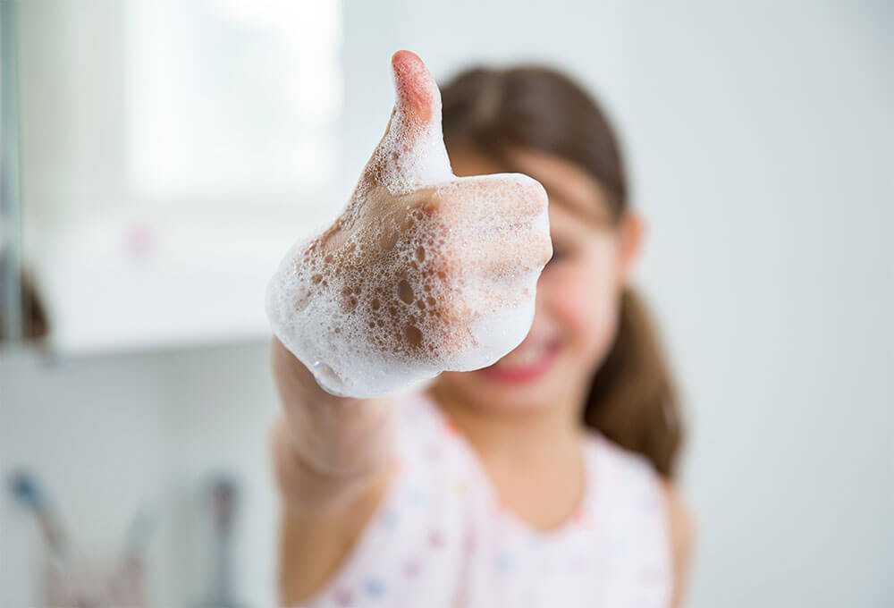Young Girl with Soapy Hands Giving a Thumbs Up