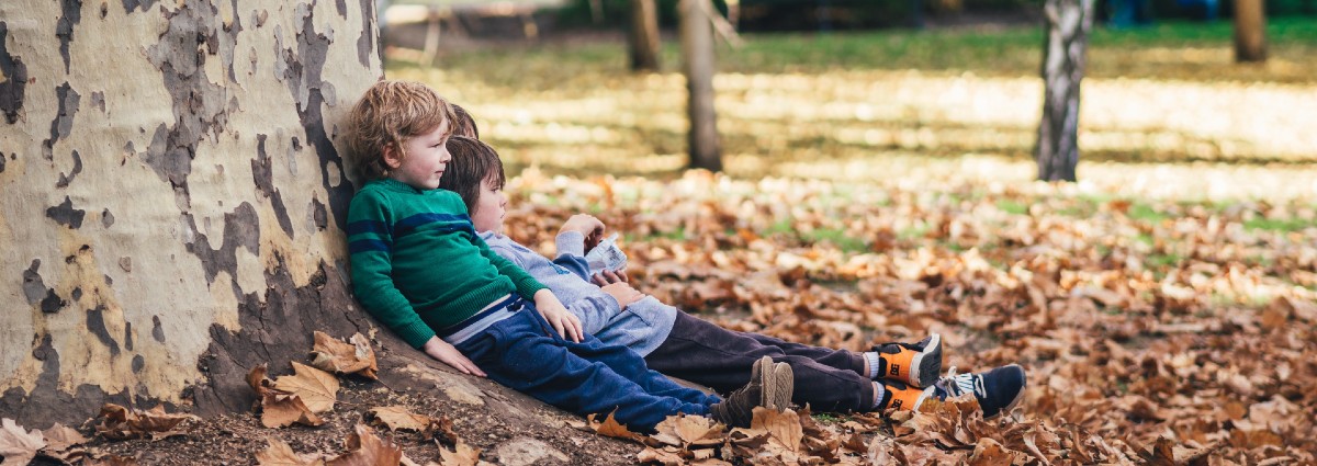 children sitting against tree