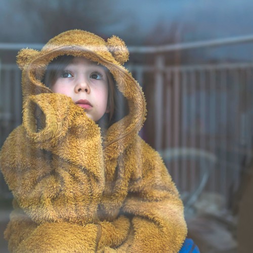 child looking sad next to window