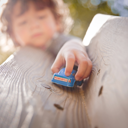 young boy playing with a toy car