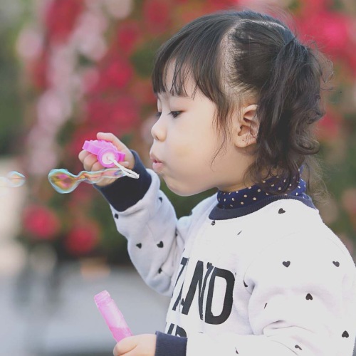 young girl blowing bubbles