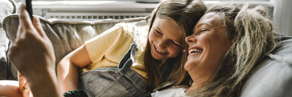 A mother and daughter on the sofa looking at a phone.jpg