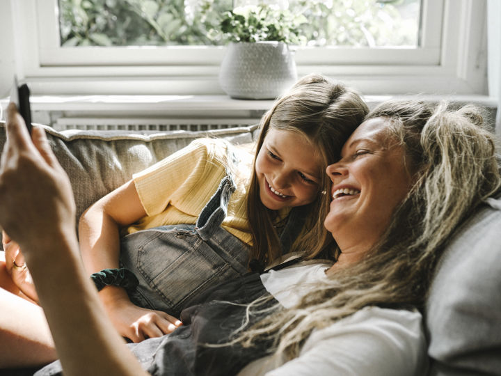 A mother and daughter on the sofa looking at a phone.jpg