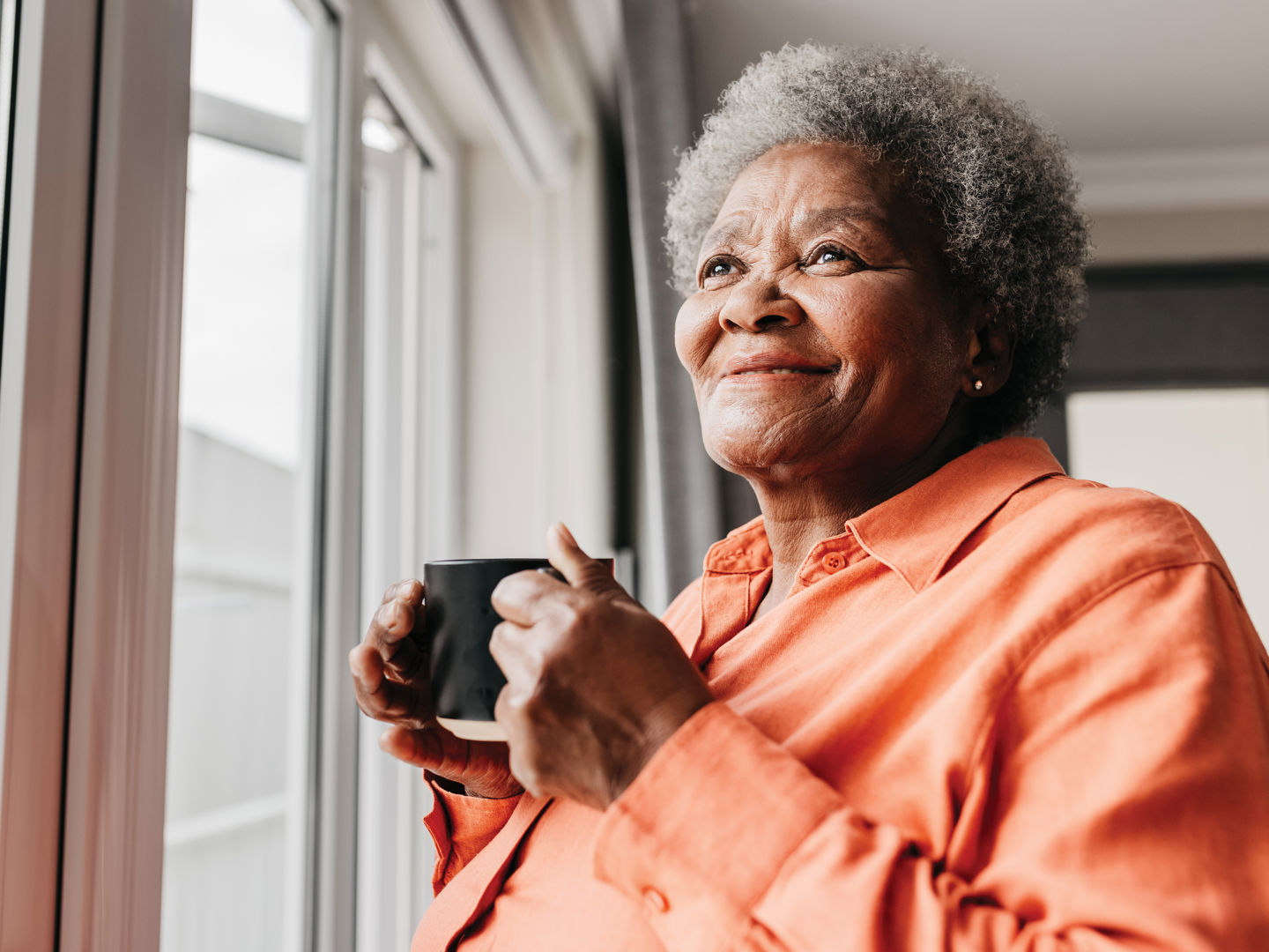 Woman drinking from a mug looking out of window