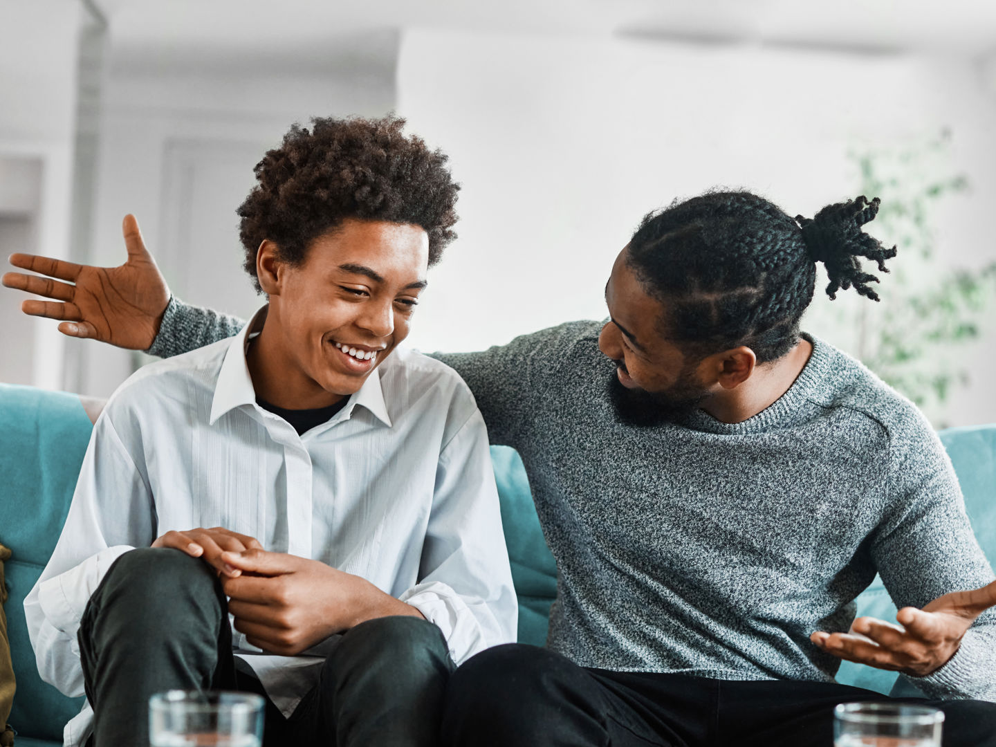 Man and teenager sitting on sofa