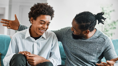 Man and teenager sitting on sofa
