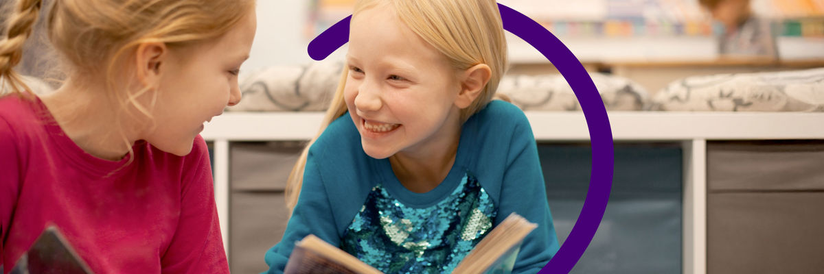 Two young children reading a book in a classroom - with Clinical Partners brand expression.jpg
