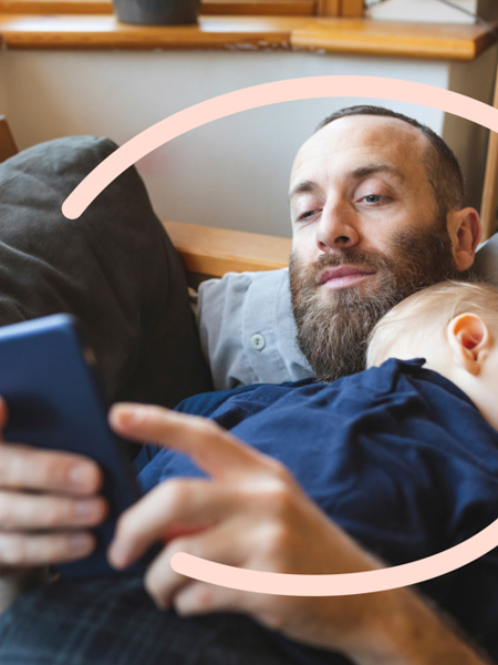 Man on sofa with baby and looking at phone.jpg