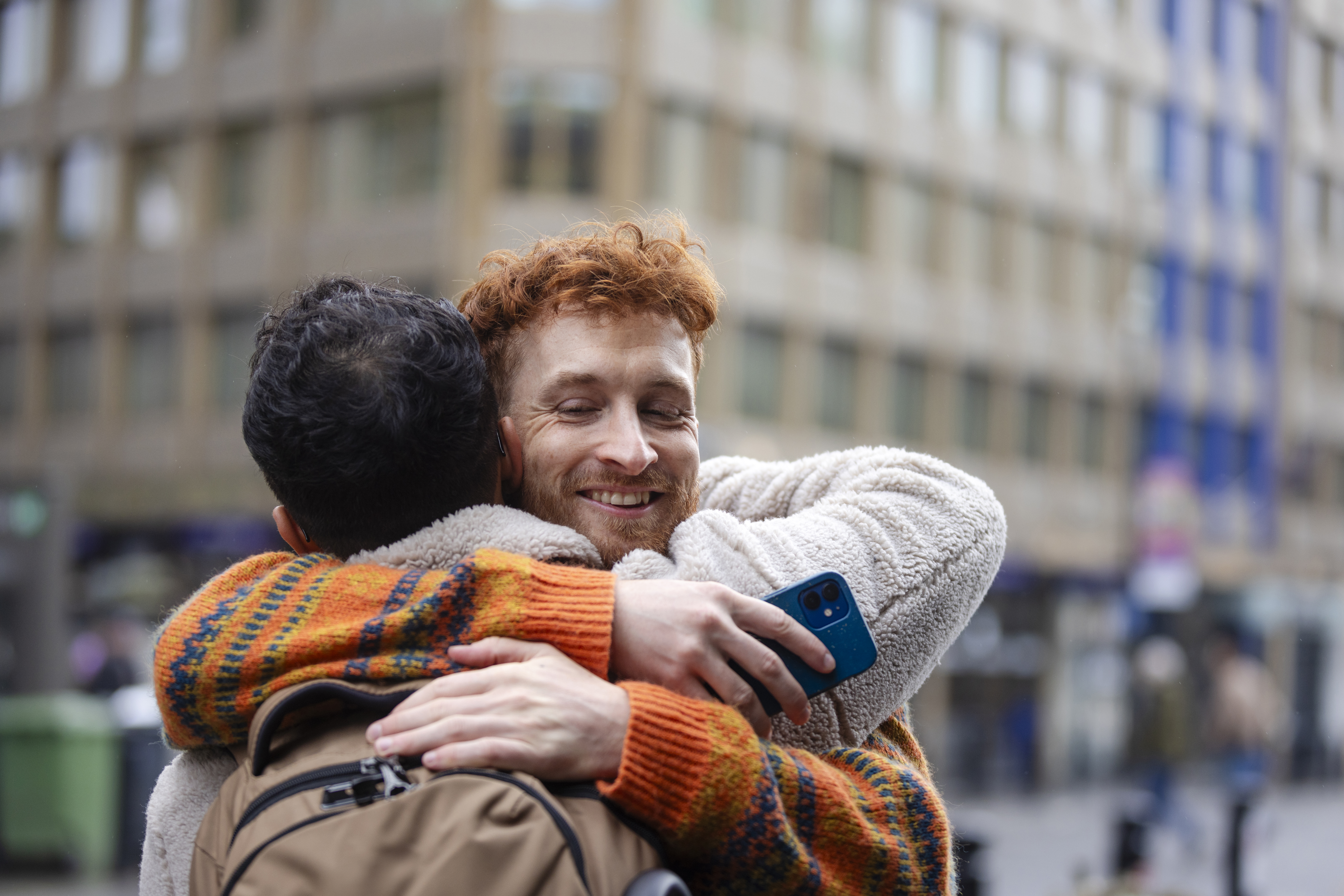 Two friends hugging in a city.jpg