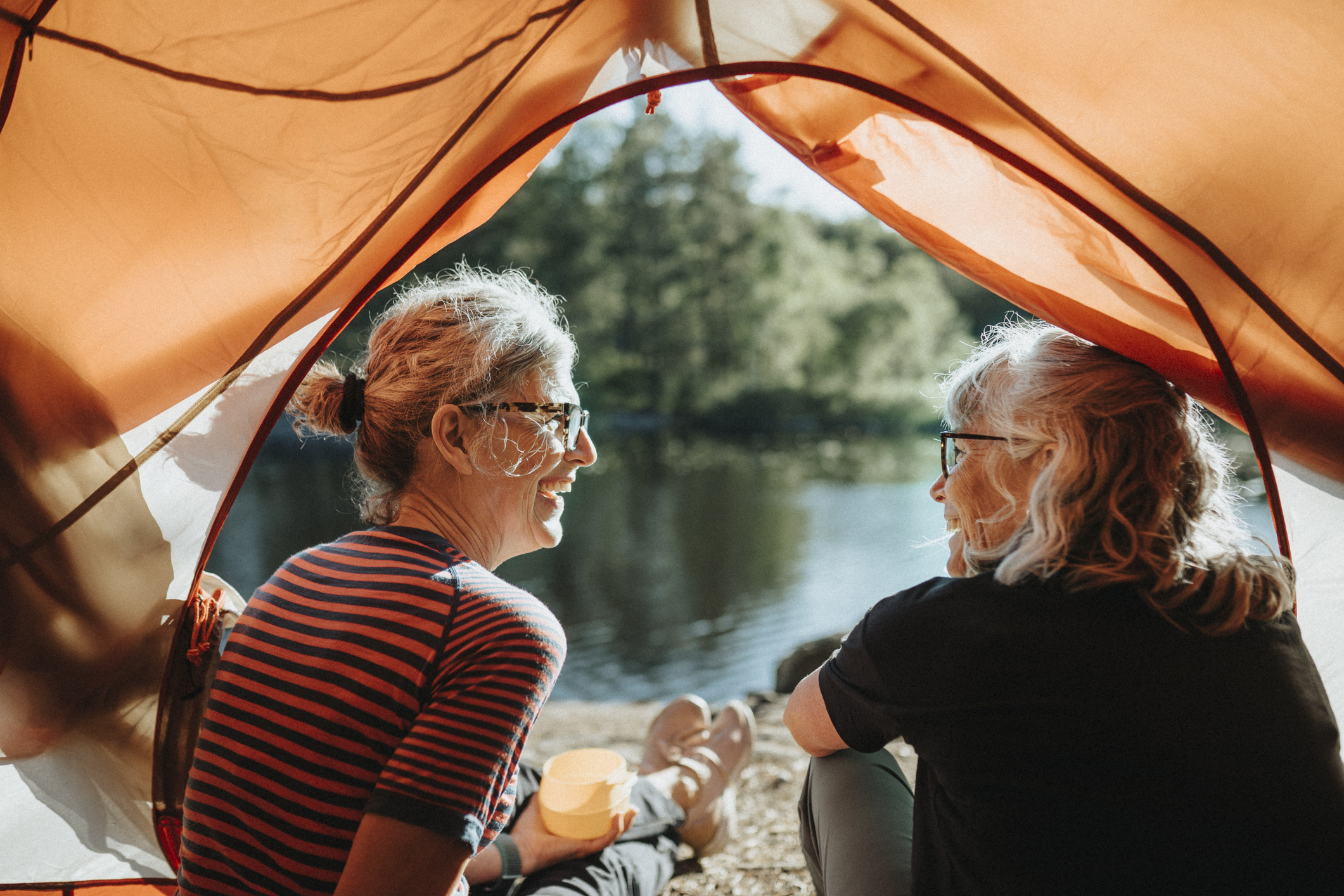 Two people camping looking out from a tent.jpg