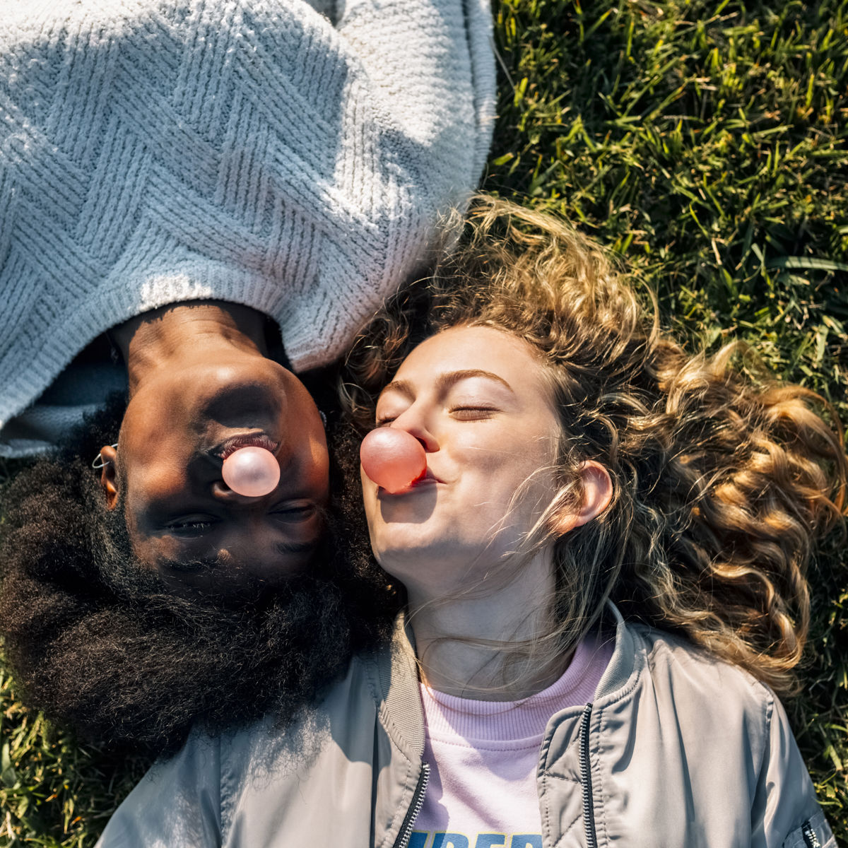 Two women lying on grass blowing bubblegum bubbles.jpg