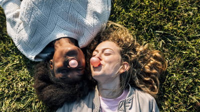 Two women lying on grass blowing bubblegum bubbles.jpg