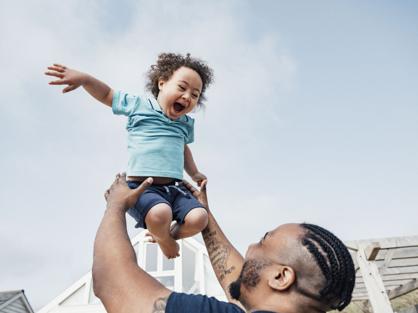 Man playfully lifting small child above his head