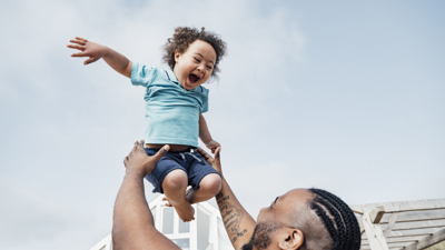 Man playfully lifting small child above his head.jpg
