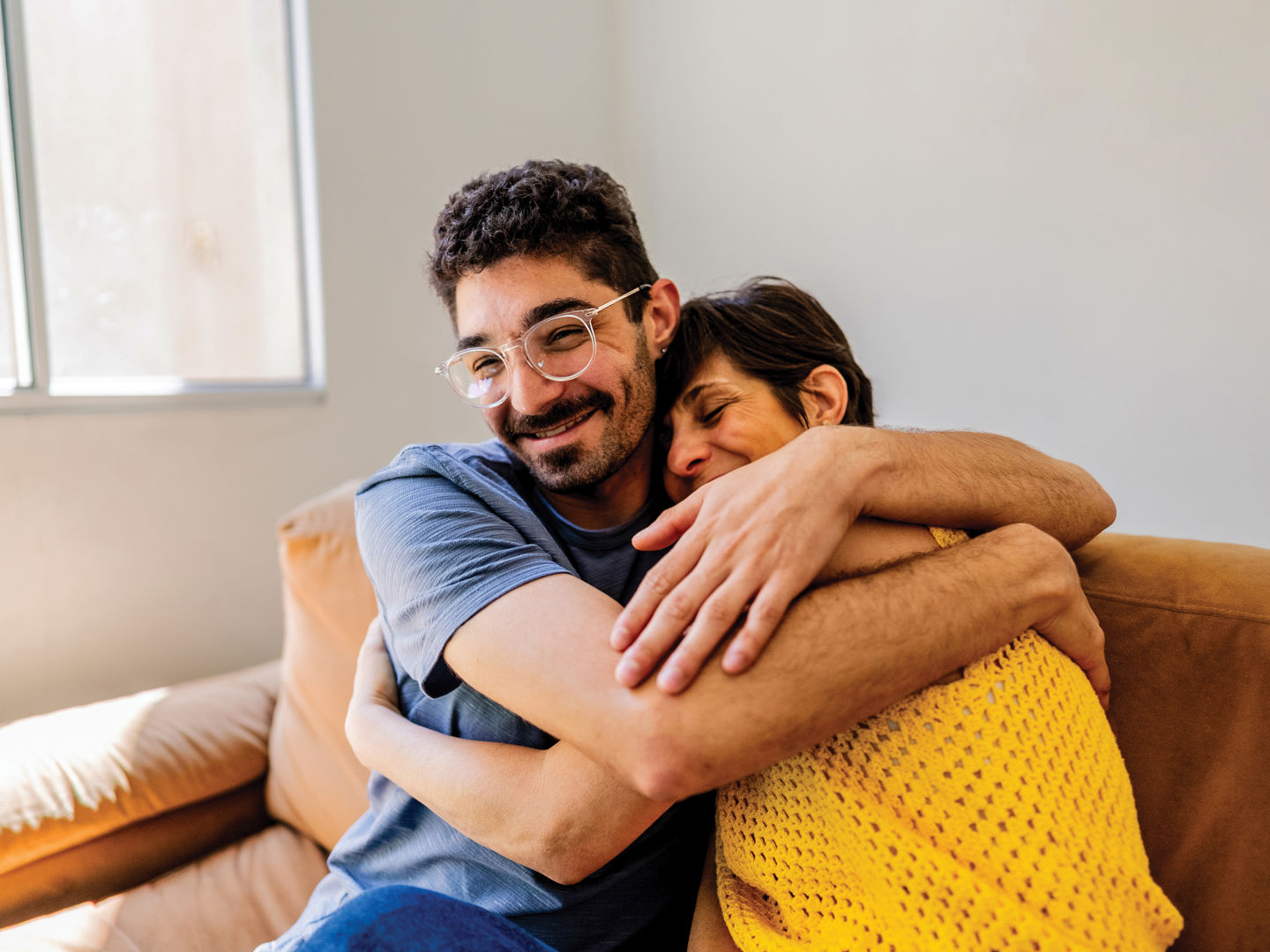 Two people sitting on a sofa in a friendly embrace